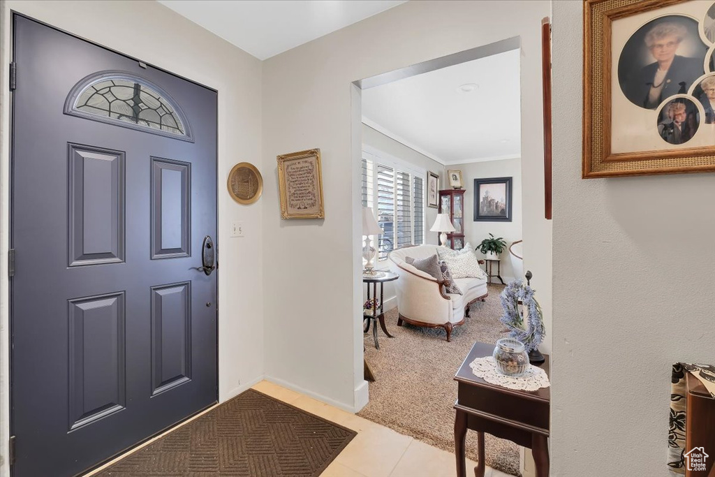 Tiled foyer featuring baseboards and carpet