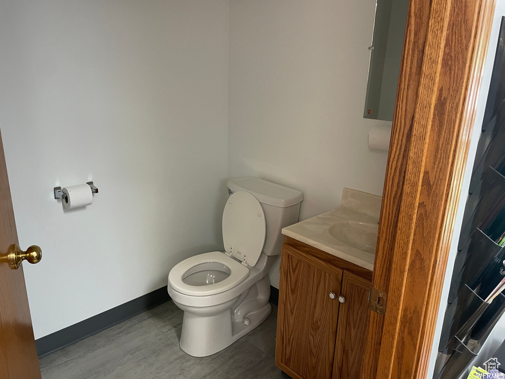 Bathroom with baseboards, toilet, wood finished floors, and vanity