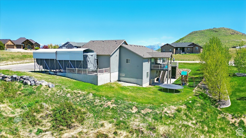Rear view of house featuring stairway, a lawn, a deck with mountain view, and a residential view