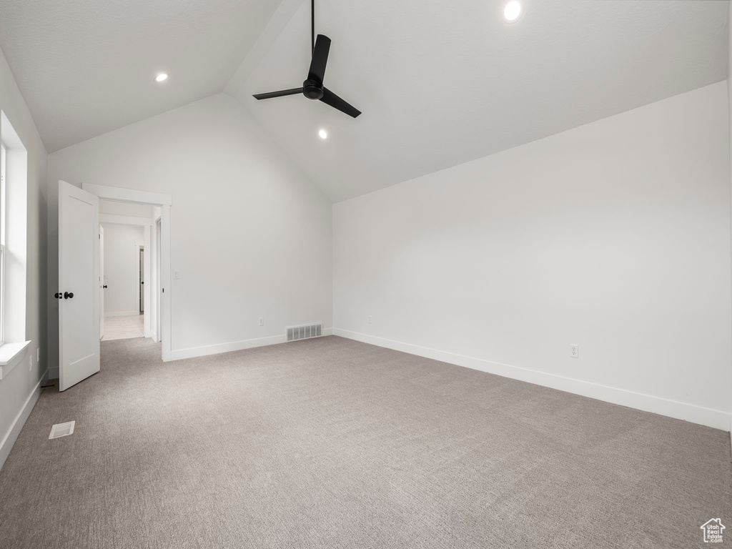 Interior space featuring visible vents, a ceiling fan, baseboards, carpet, and lofted ceiling