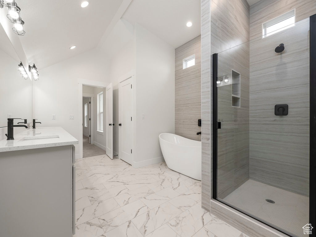 Full bathroom featuring vaulted ceiling, double vanity, a stall shower, a soaking tub, and marble finish floor