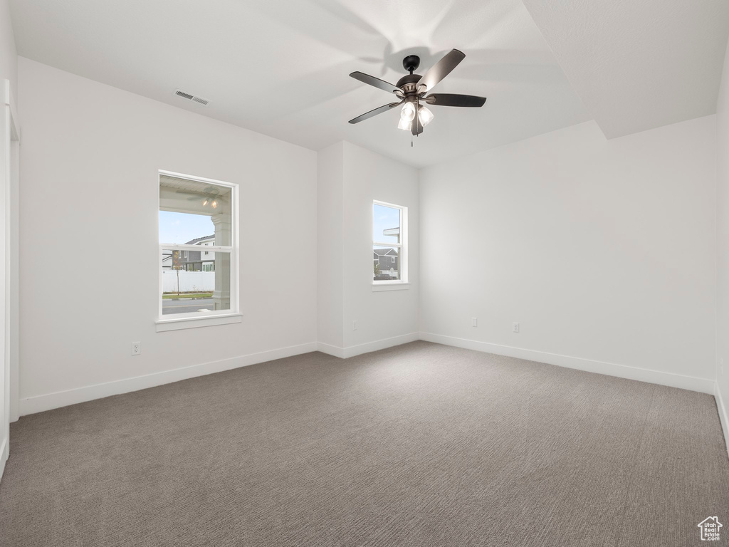 Empty room featuring a wealth of natural light, baseboards, a ceiling fan, and carpet flooring
