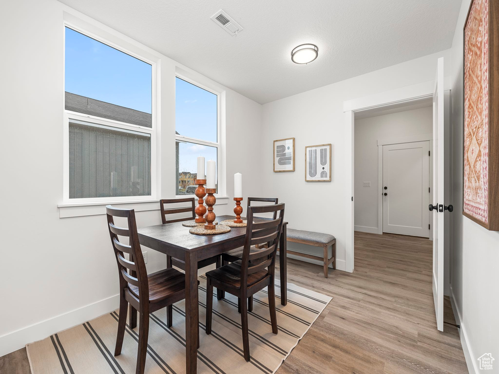 Dining room with light wood-type flooring, visible vents, and baseboards
