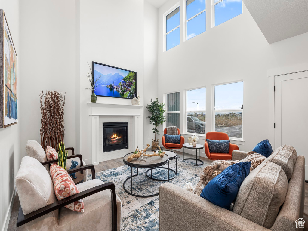 Living room featuring a glass covered fireplace, wood finished floors, and a towering ceiling