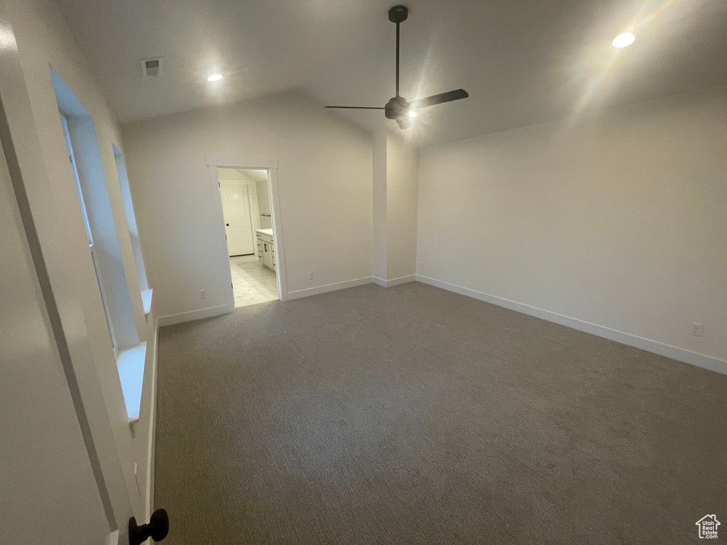 Carpeted empty room featuring baseboards, lofted ceiling, visible vents, and a ceiling fan