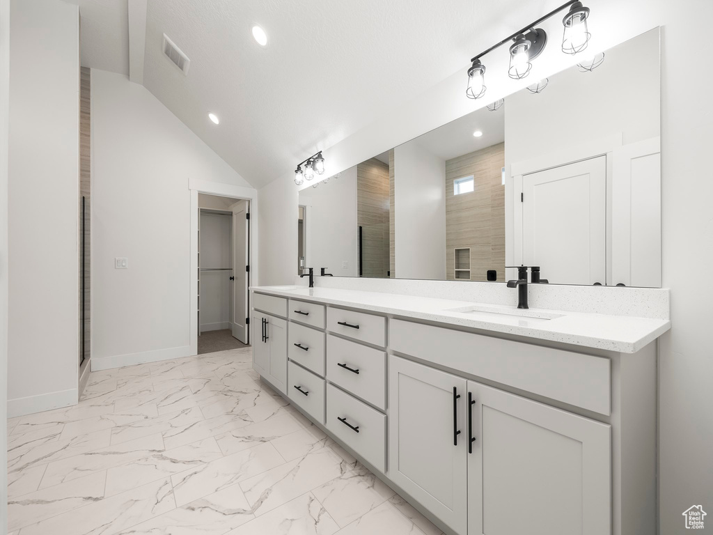 Bathroom featuring visible vents, double vanity, a sink, vaulted ceiling, and marble finish floor