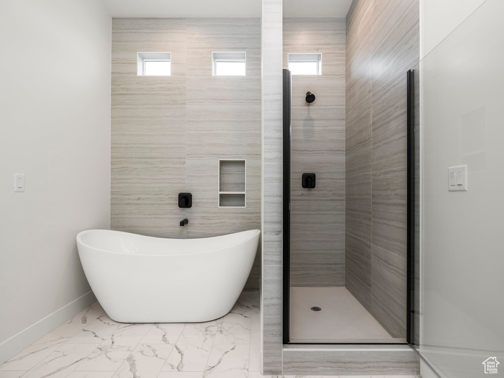 Full bathroom with baseboards, a soaking tub, plenty of natural light, a shower stall, and marble finish floor
