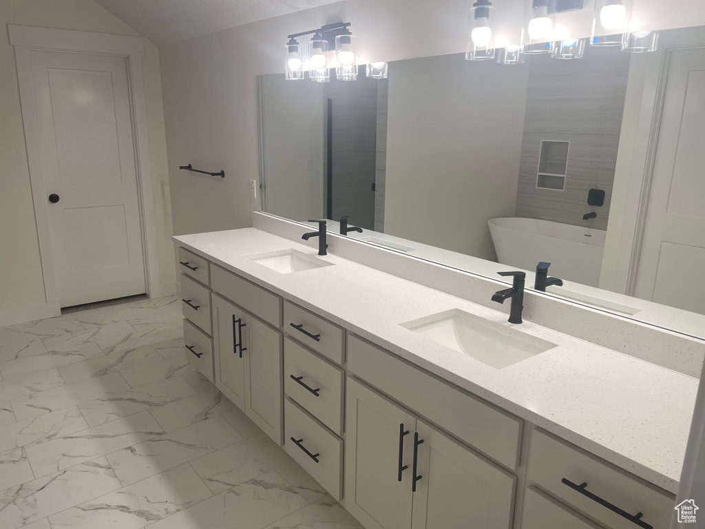Bathroom featuring marble finish floor, a freestanding bath, and a sink