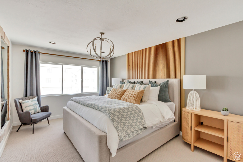 Bedroom featuring baseboards, light carpet, and a chandelier
