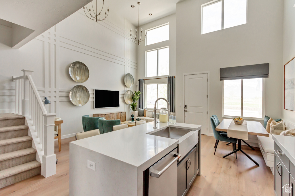 Kitchen with light wood-type flooring, a sink, light countertops, stainless steel dishwasher, and open floor plan