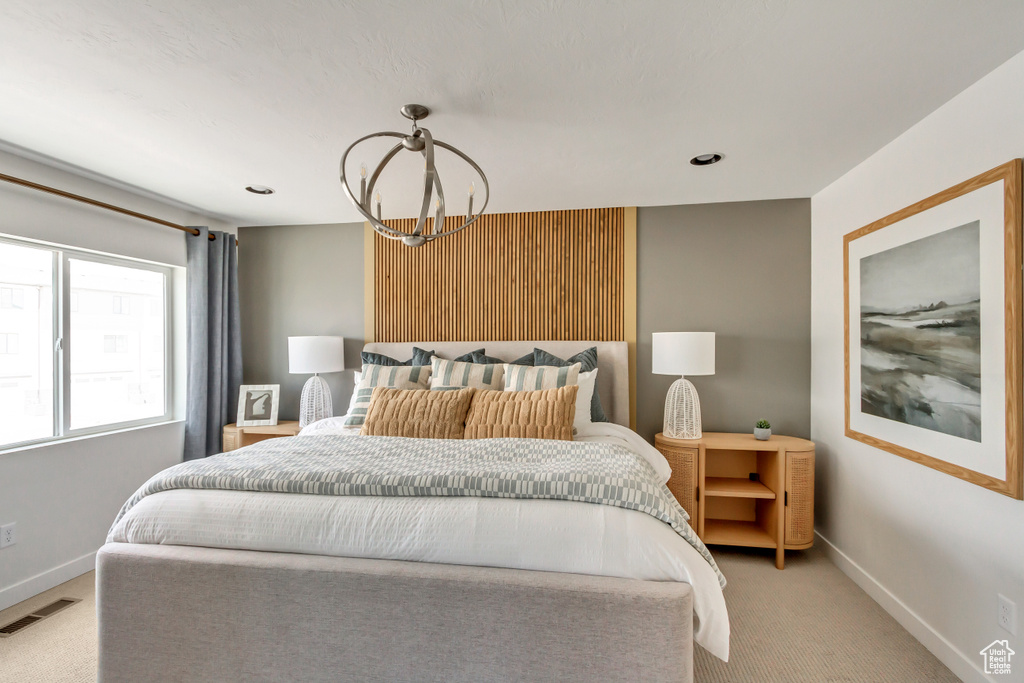 Bedroom featuring visible vents, baseboards, light carpet, and an inviting chandelier