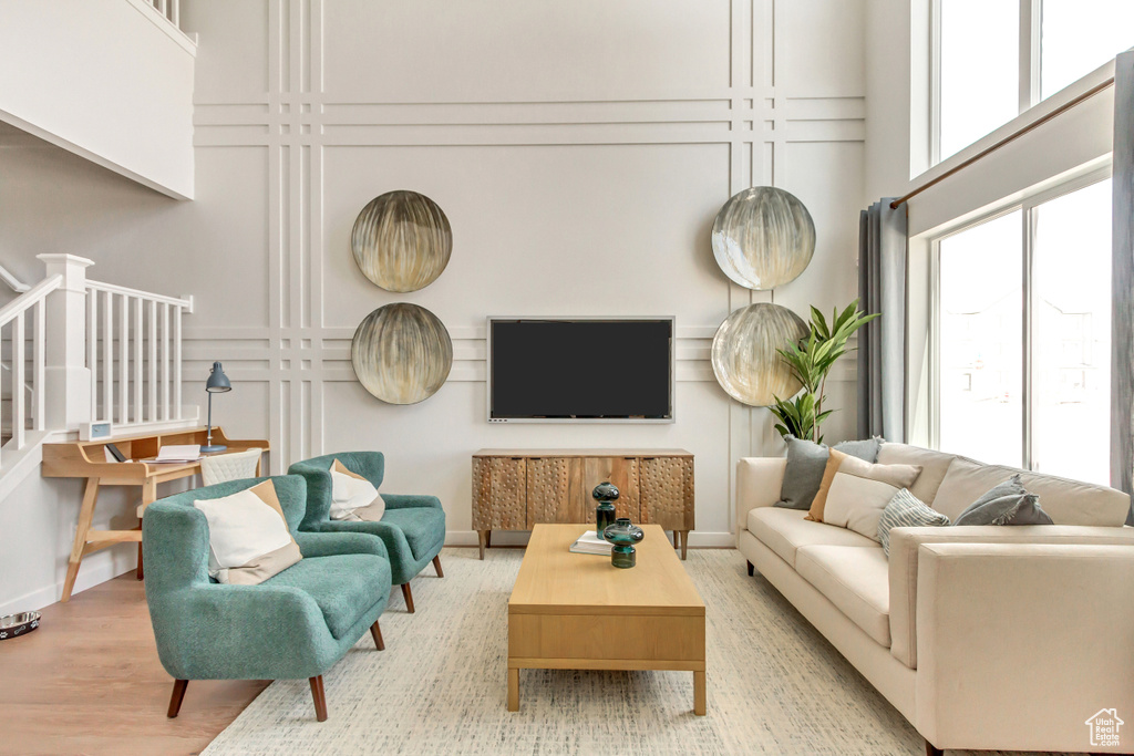 Living room with baseboards, a high ceiling, wood finished floors, and a decorative wall