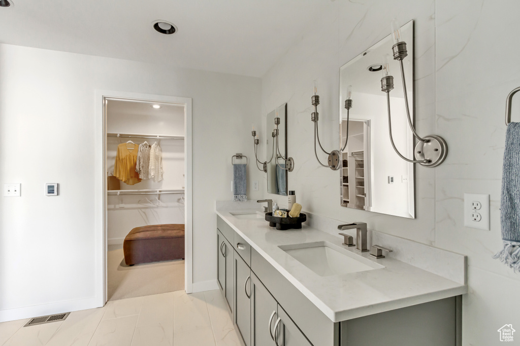 Full bath featuring a sink, a walk in closet, visible vents, and double vanity