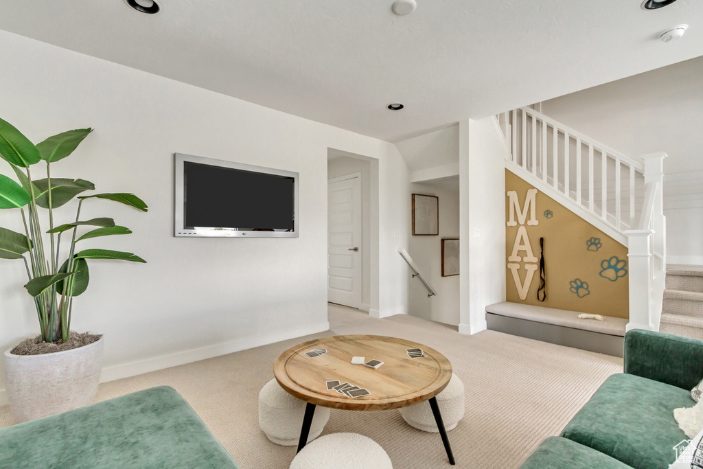 Living area featuring light colored carpet, stairs, and baseboards