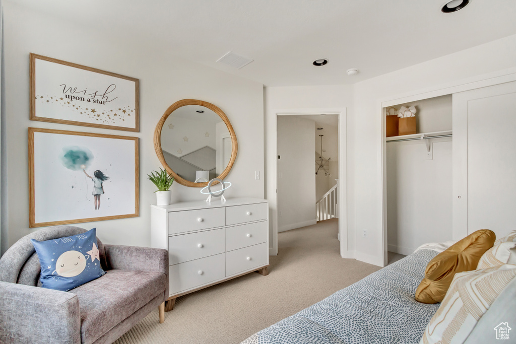 Bedroom featuring light carpet, visible vents, baseboards, and a closet