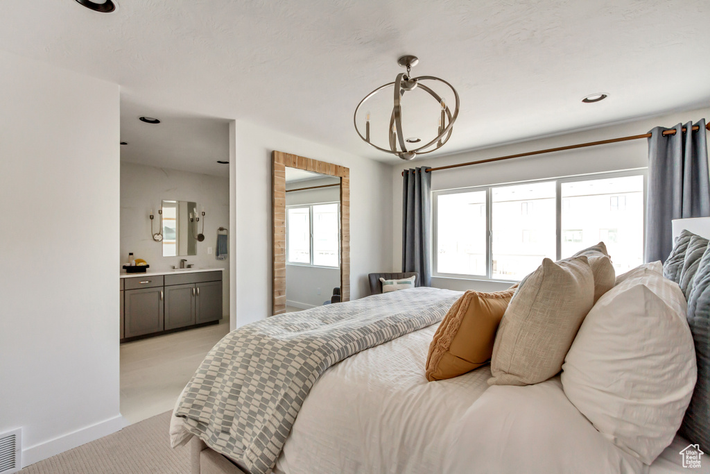 Bedroom with baseboards, ensuite bath, a sink, light carpet, and a chandelier
