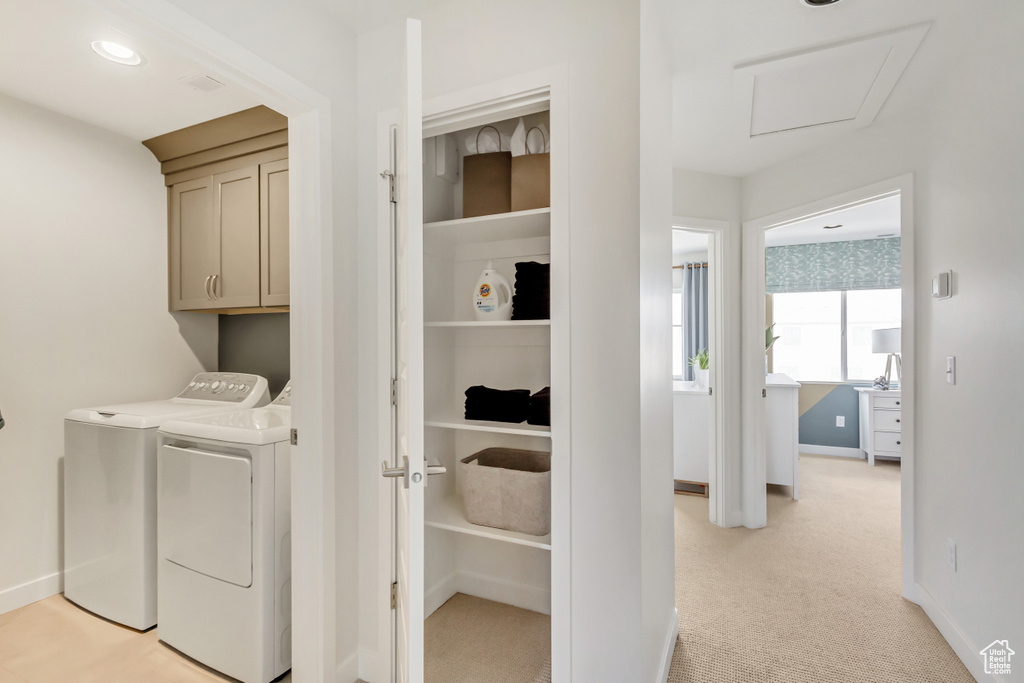 Laundry area featuring light carpet, washer and dryer, cabinet space, baseboards, and attic access