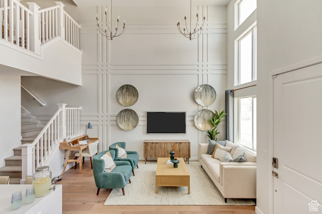 Living area featuring a notable chandelier, stairway, a towering ceiling, and wood finished floors