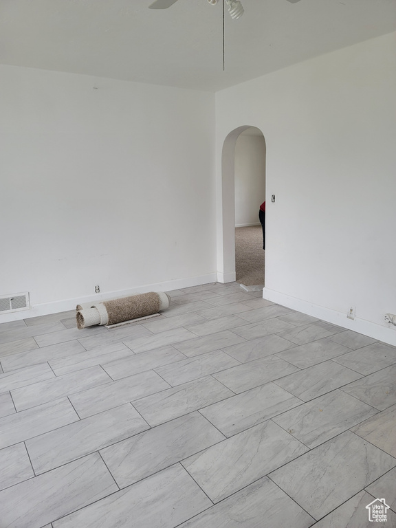 Spare room with arched walkways, a ceiling fan, and baseboards