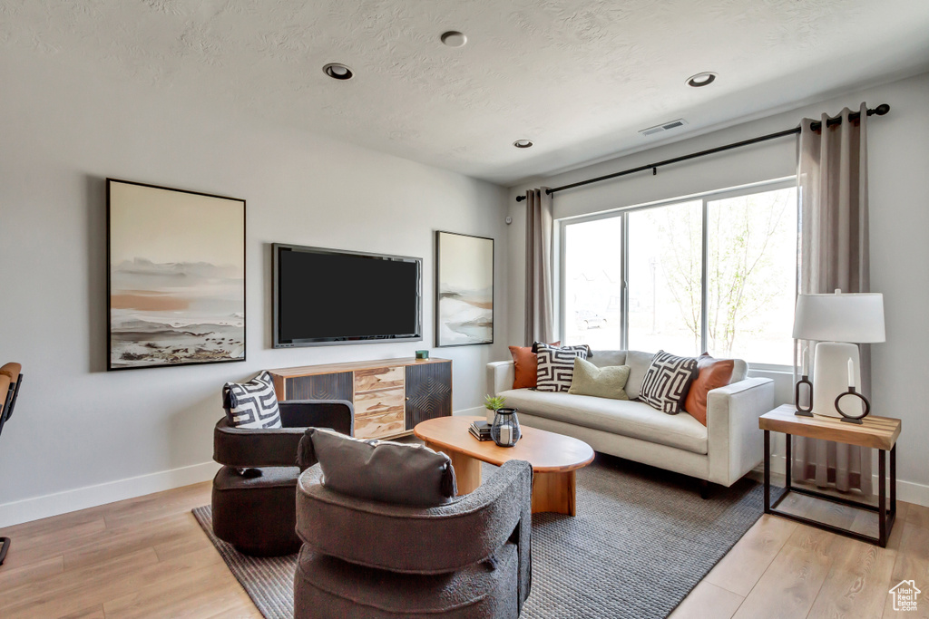 Living area with light wood-style flooring, visible vents, baseboards, and a textured ceiling