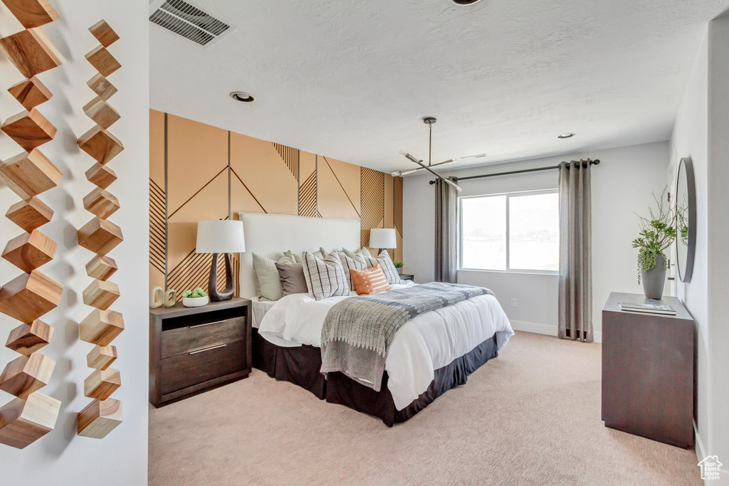 Bedroom featuring visible vents, light carpet, a textured ceiling, and baseboards