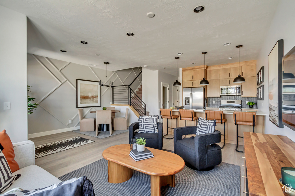 Living room featuring stairs, light wood-style flooring, baseboards, and a chandelier
