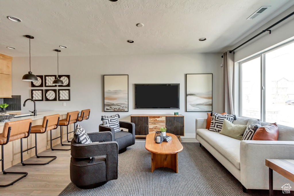Living room featuring recessed lighting, visible vents, a textured ceiling, and light wood-style flooring