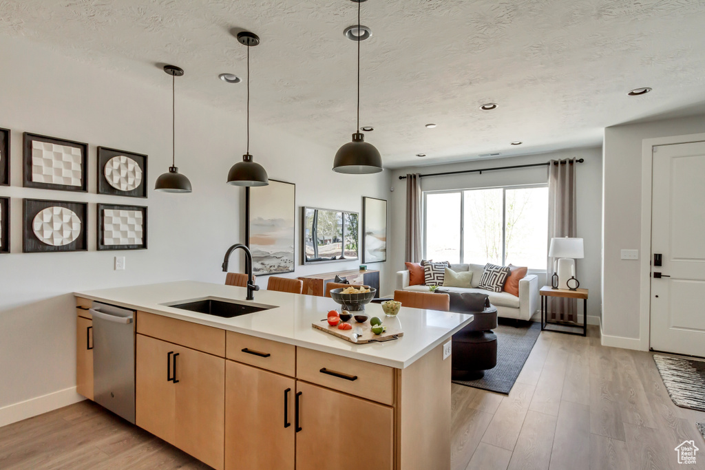 Kitchen featuring light wood-style flooring, light brown cabinetry, a sink, a peninsula, and light countertops
