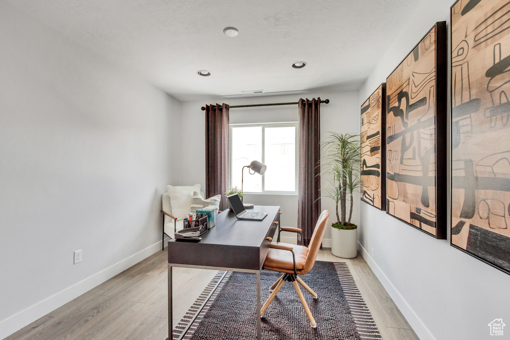 Home office with visible vents, light wood-style floors, and baseboards