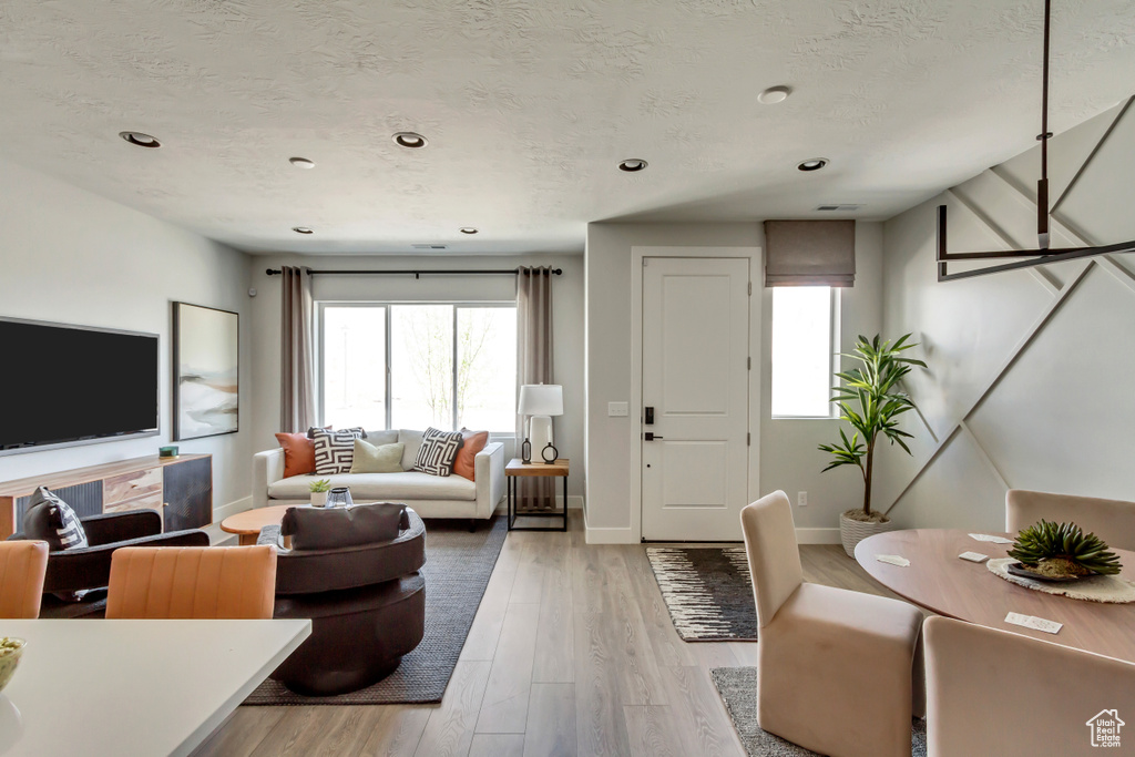 Living room featuring baseboards, plenty of natural light, a textured ceiling, and light wood-style flooring