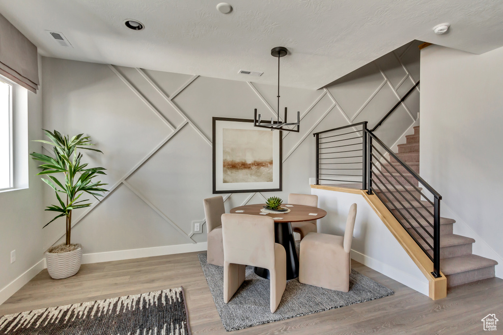 Dining space with stairs, wood finished floors, visible vents, and baseboards