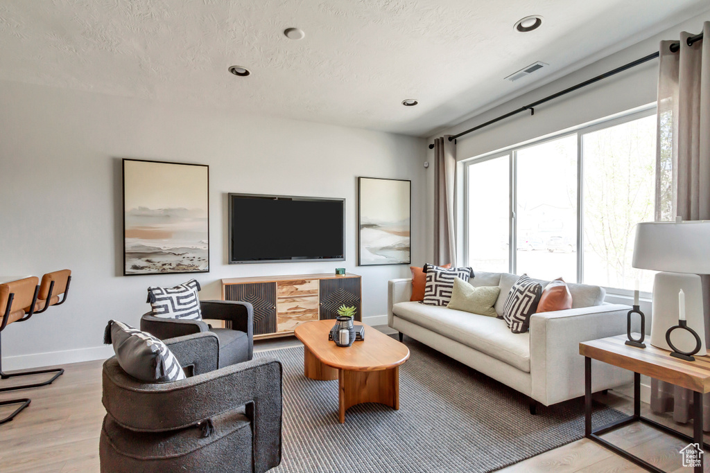 Living room with wood finished floors, baseboards, visible vents, recessed lighting, and a textured ceiling