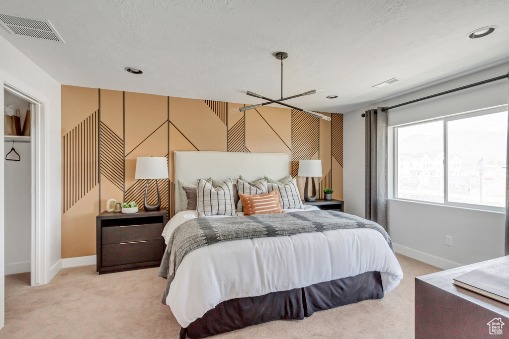 Bedroom with visible vents, light colored carpet, a textured ceiling, and baseboards