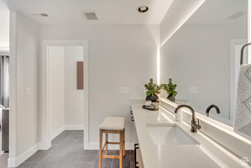 Bathroom with a sink, visible vents, baseboards, and double vanity