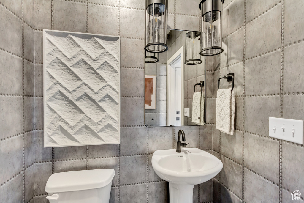 Bathroom featuring toilet, tile walls, and a sink