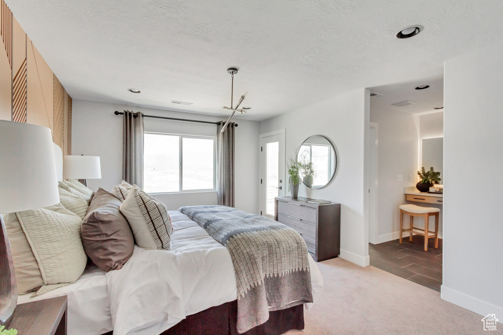 Bedroom with light carpet, a textured ceiling, and baseboards
