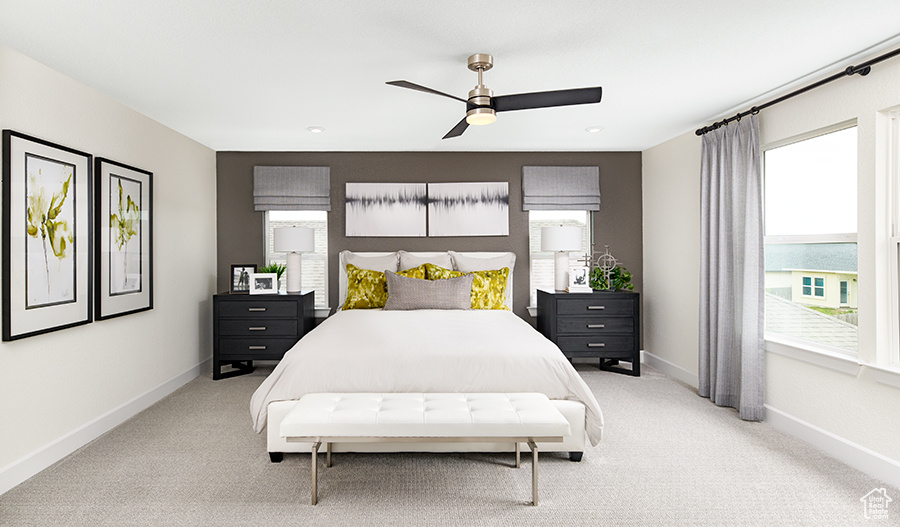 Bedroom with light colored carpet, baseboards, and ceiling fan