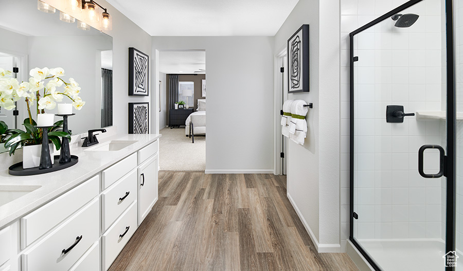 Full bath with a healthy amount of sunlight, a stall shower, wood finished floors, and a sink