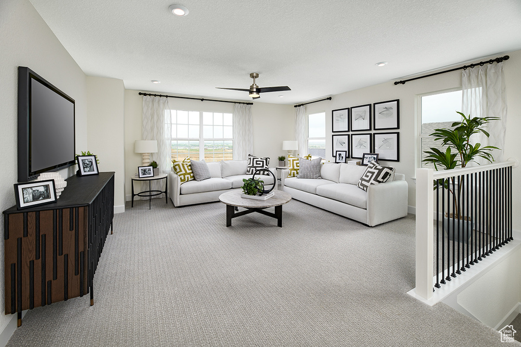 Carpeted living room featuring baseboards, a textured ceiling, and a ceiling fan
