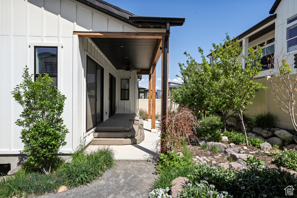 View of side of home featuring ceiling fan, board and batten siding, and fence