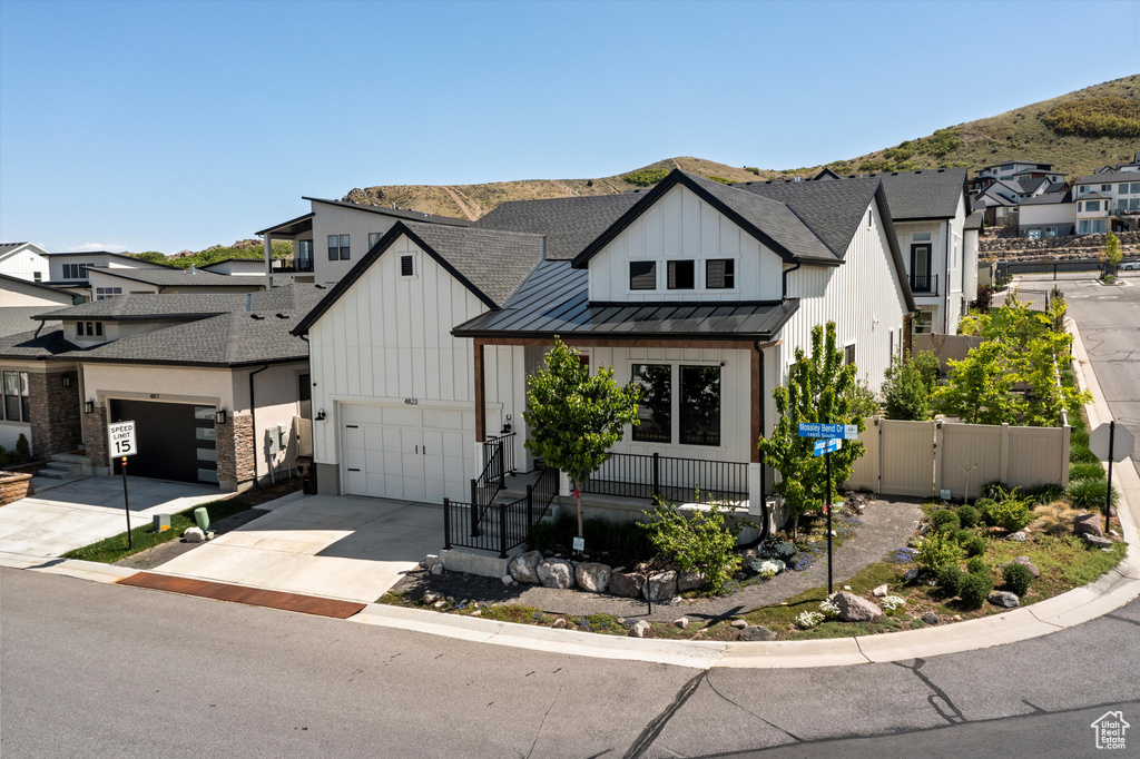 Modern farmhouse with a standing seam roof, board and batten siding, concrete driveway, a mountain view, and covered porch