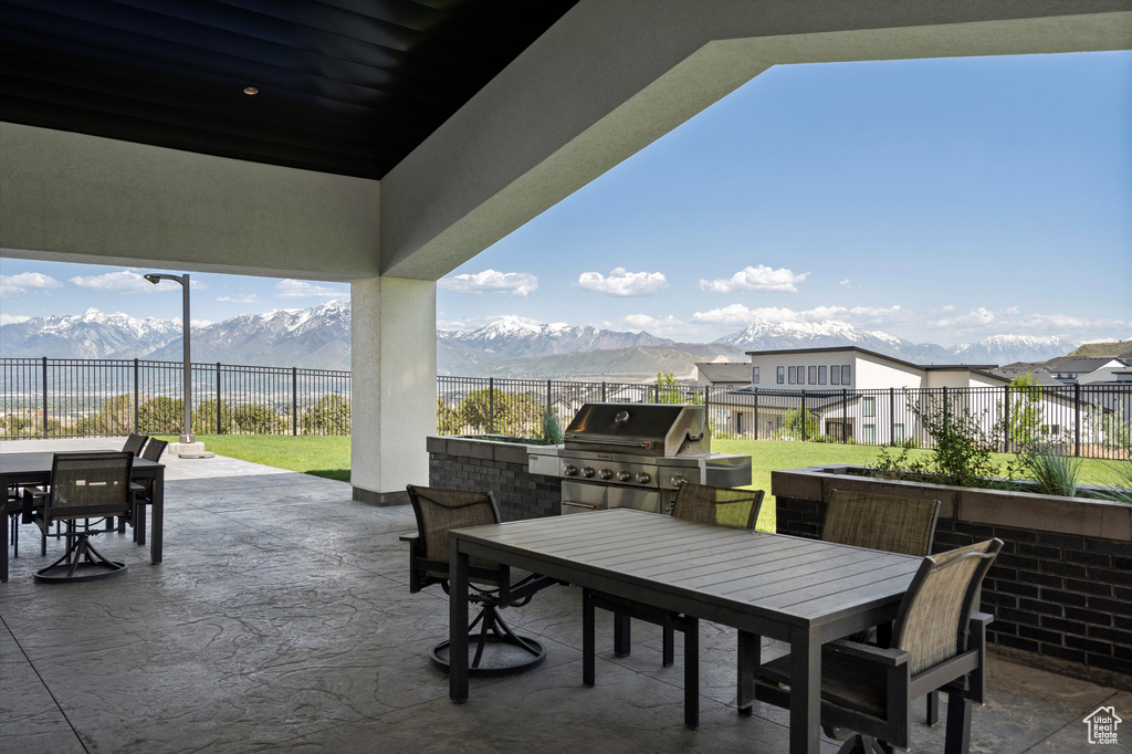 View of patio featuring outdoor dining space, grilling area, exterior kitchen, and a mountain view