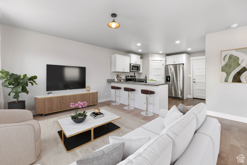 Living room featuring dark wood-style flooring, recessed lighting, and baseboards