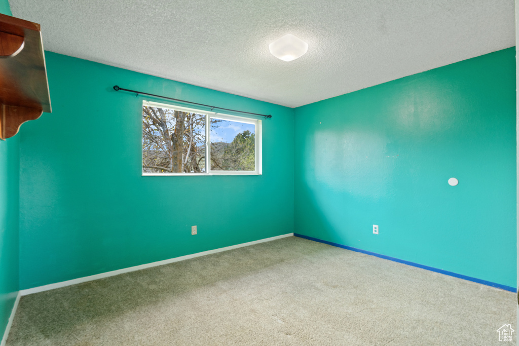 Spare room featuring baseboards, carpet, and a textured ceiling
