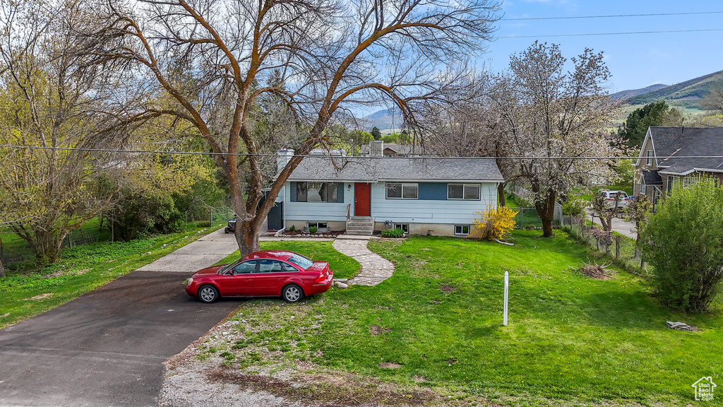 View of front of house featuring fence, a mountain view, driveway, and a front yard