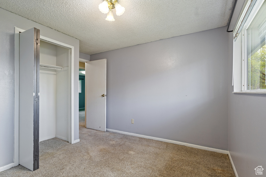 Unfurnished bedroom featuring a closet, baseboards, carpet flooring, and a textured ceiling