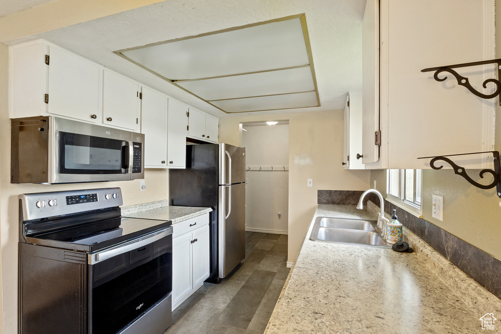Kitchen with a sink, light countertops, white cabinets, and stainless steel appliances
