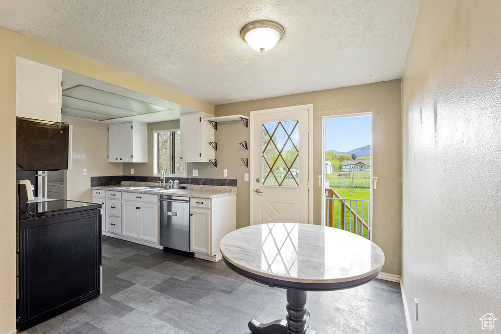 Kitchen with white cabinets, a textured ceiling, a sink, and dishwasher