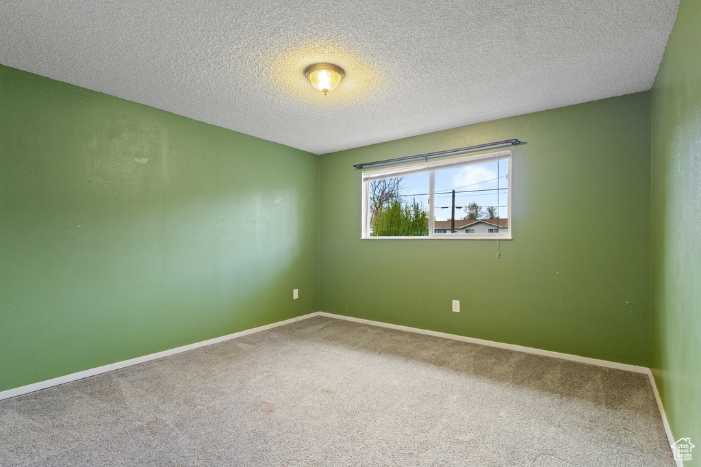 Empty room featuring baseboards, carpet flooring, and a textured ceiling