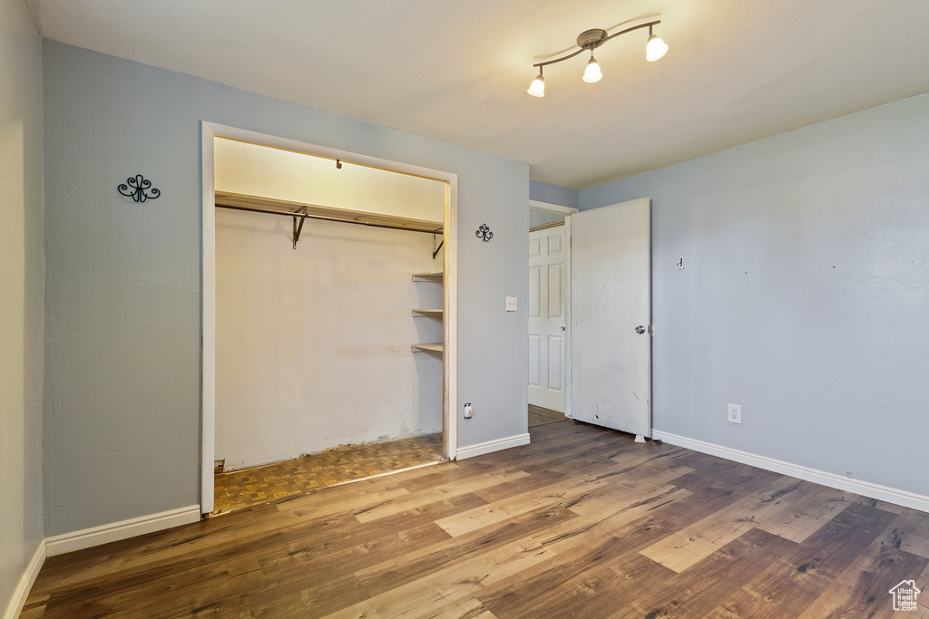 Unfurnished bedroom with baseboards, wood finished floors, and a closet